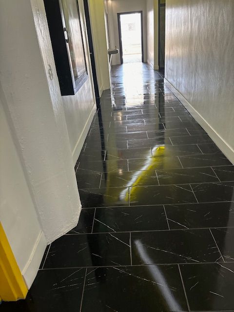 A long hallway with black tiles and a yellow caution sign.