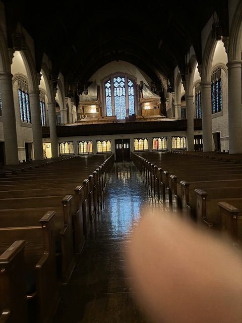 A church with rows of wooden benches and a large window