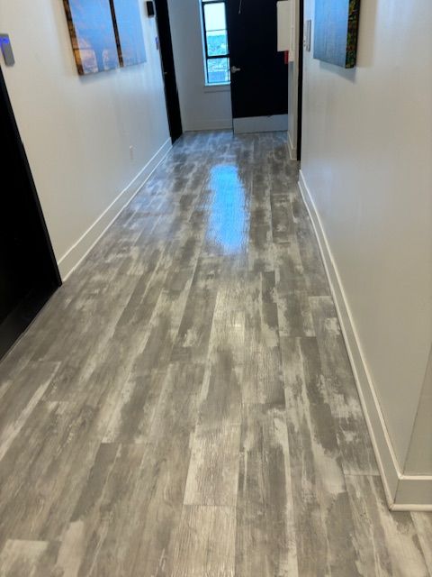 A hallway with a wooden floor and white walls.