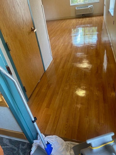 A mop is sitting on a wooden floor in a hallway.