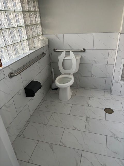 A bathroom with a toilet and a hand rail