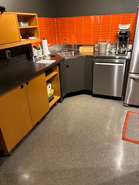 A kitchen with stainless steel appliances and orange tiles