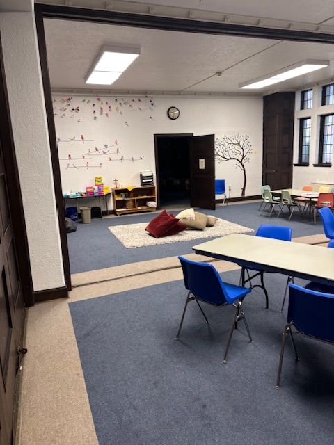 A room with tables and chairs and a tree on the wall