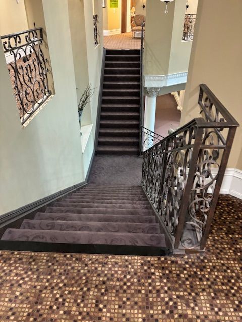 A staircase with a wrought iron railing and a carpeted floor