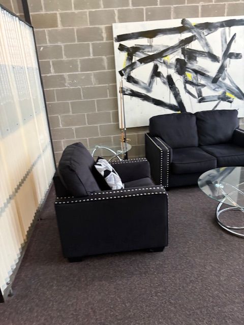 A living room with black furniture and a painting on the wall