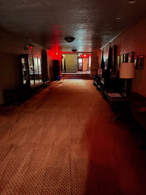 A long hallway with a red carpet and stairs in the background.