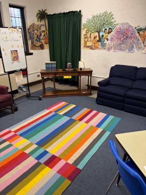 A room with a colorful rug and a white board that says 