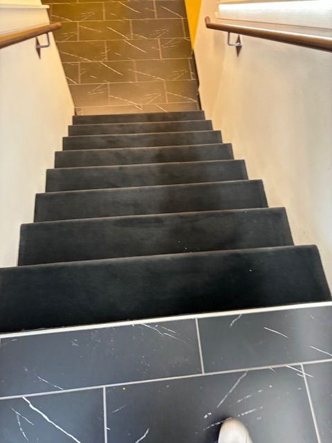 A person is walking down a set of black stairs