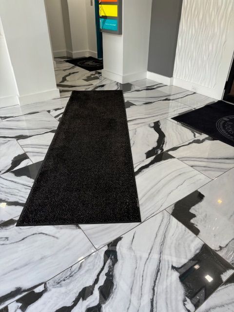 A black and white marble floor with a black rug