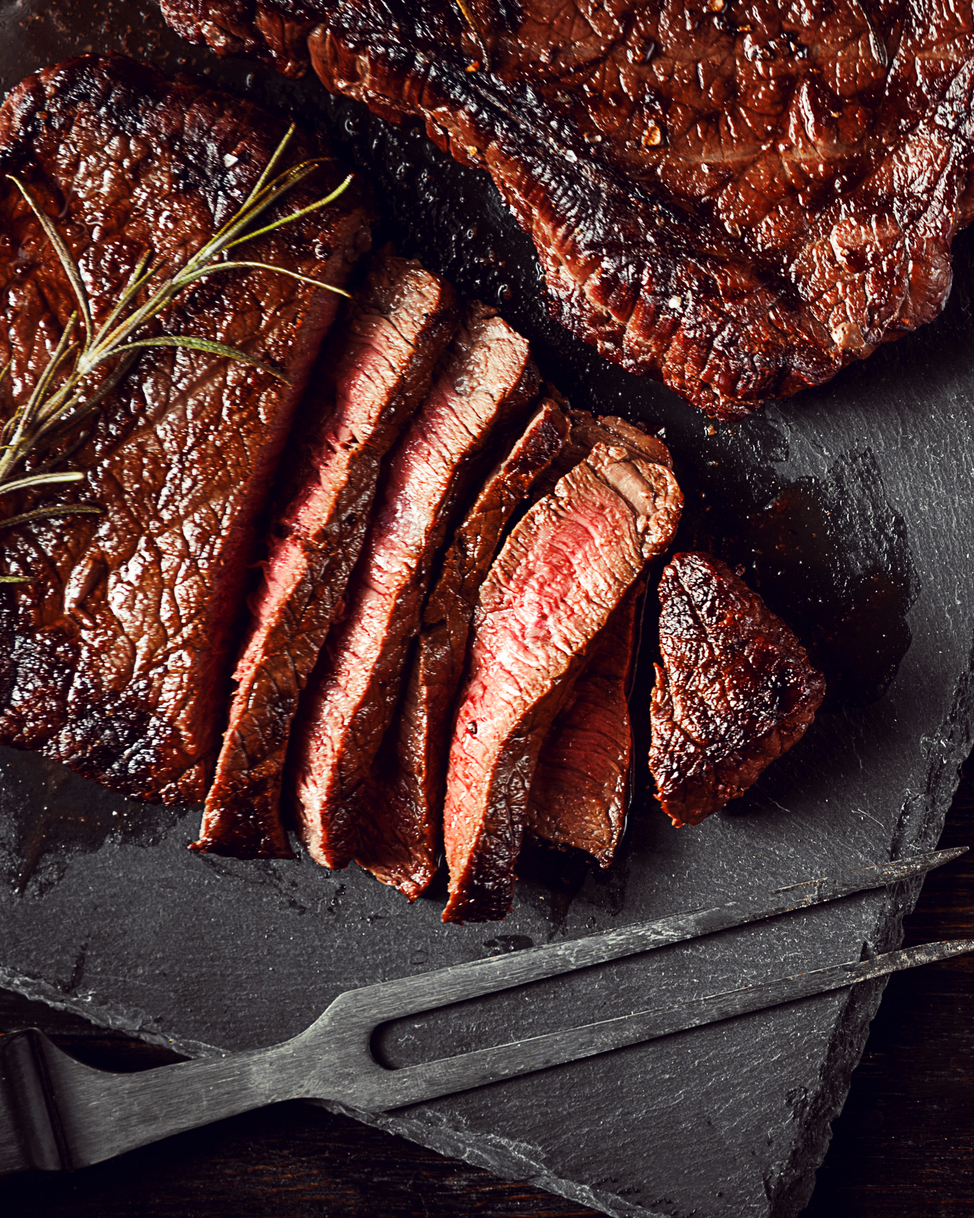 Un gros plan d'un steak sur une planche à découper avec une fourchette.