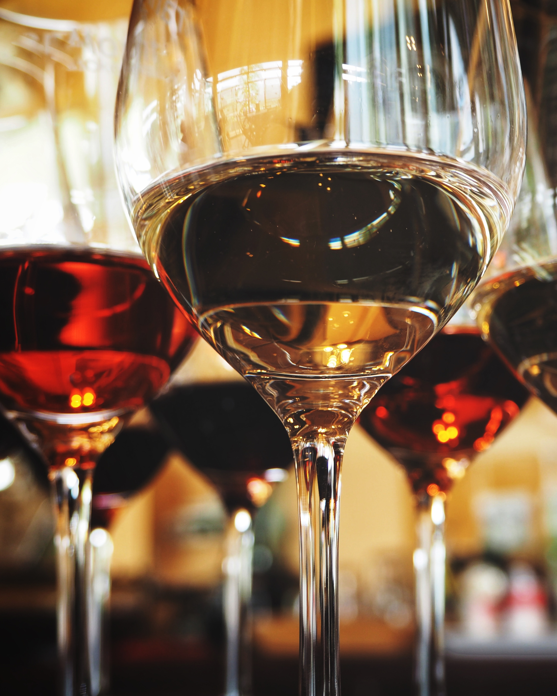 Une rangée de verres à vin remplis de différents types de vins