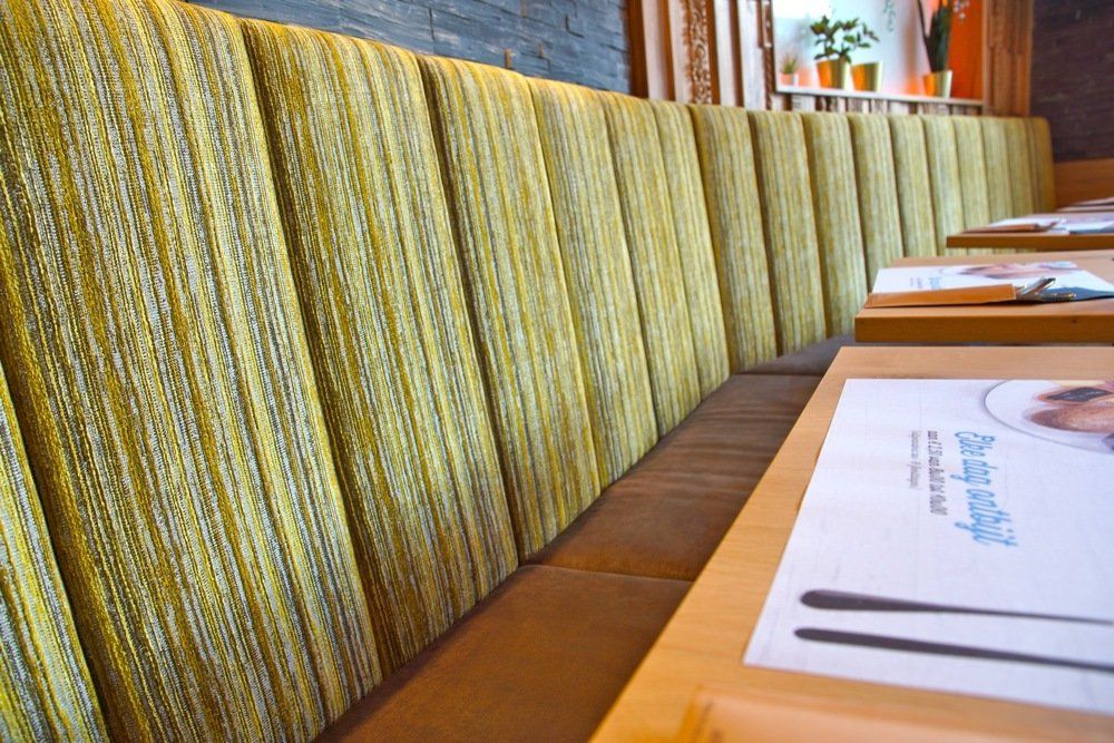 Zitbanken op maat. Gestoffeerde zetels. Afwerking naar keuze: rug met verticale banen. Stofferen maatwerk zitbanken. Schrijnwerkerij. Stoffeerderij. Maatwerk. Ontwerp interieurbouwers, interieurdesigners, interieurarchitecten. Voor horeca, retail, zorg en bedrijven.