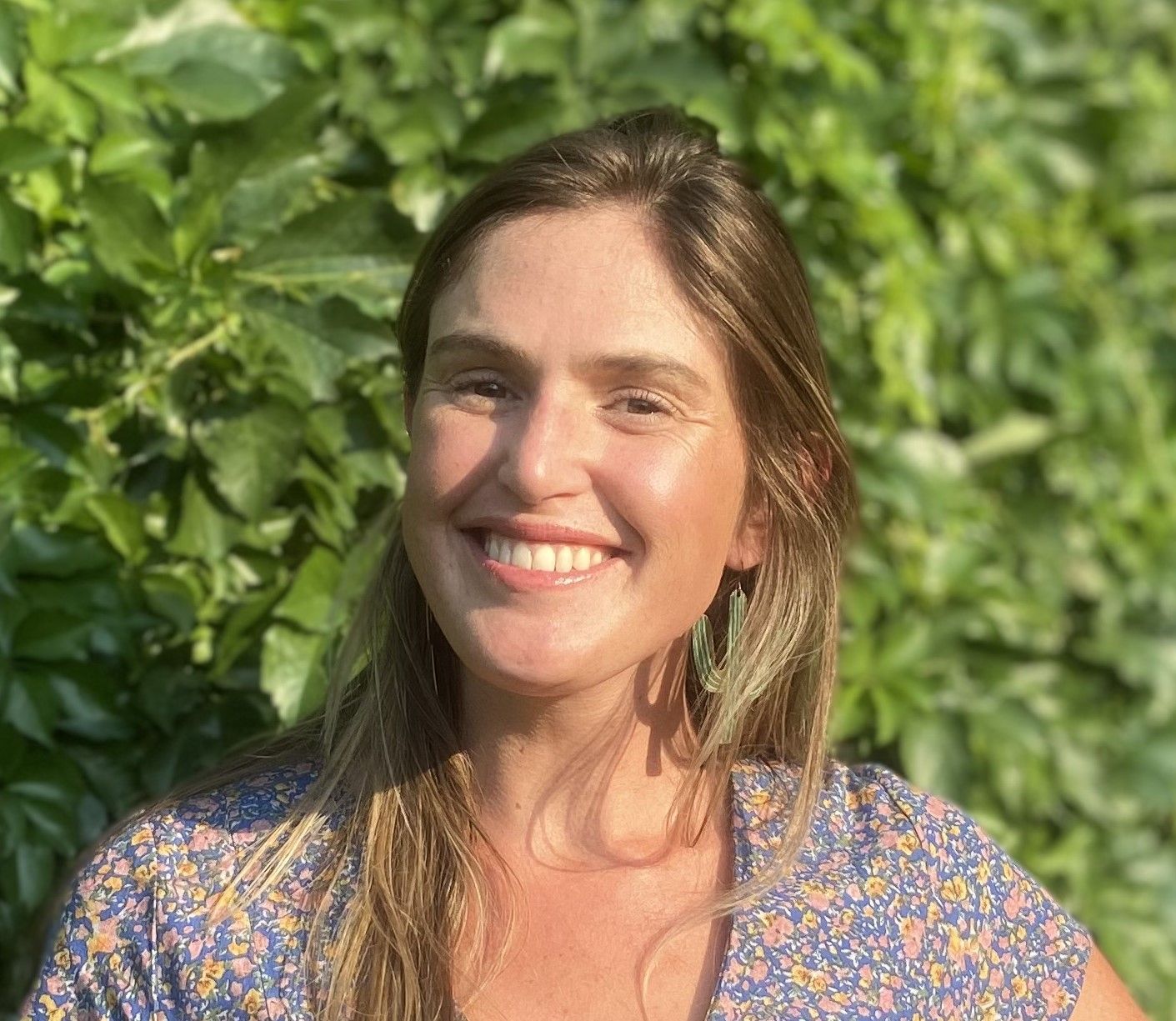 a woman in a green dress and earrings is smiling for the camera .