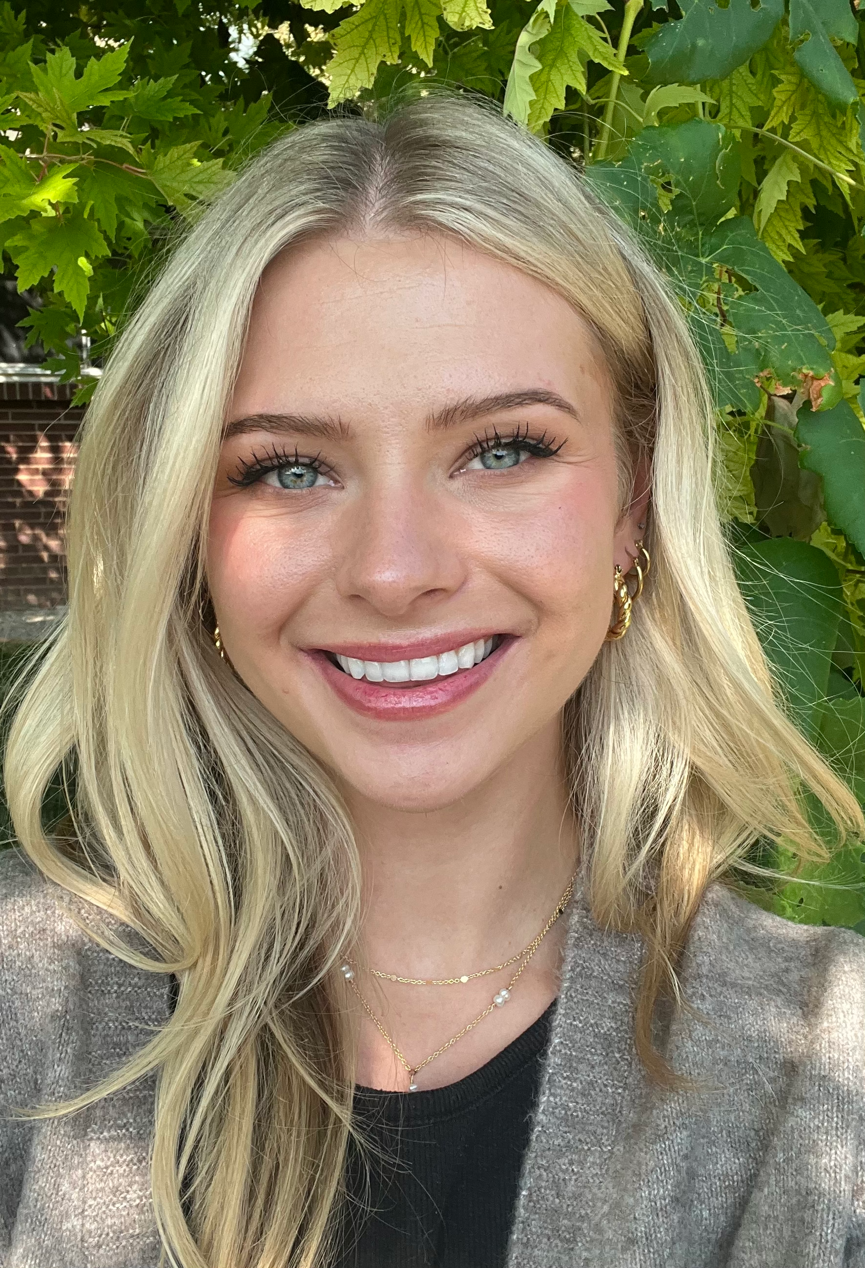 a woman in a green dress and earrings is smiling for the camera .