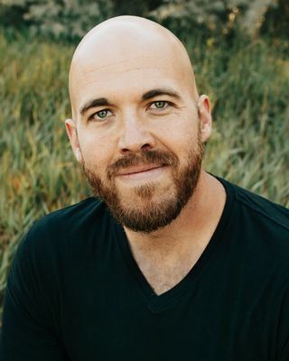 a bald man with a beard is wearing a black shirt and smiling .