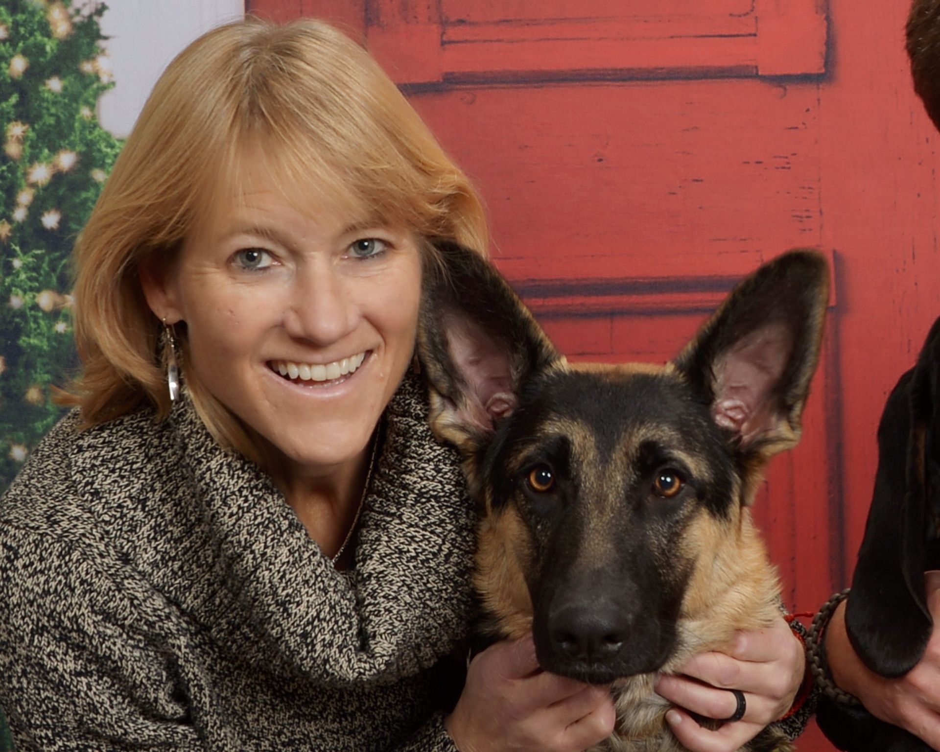 a woman is holding a german shepherd in front of a red door