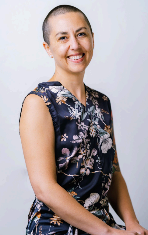 a woman in a green dress and earrings is smiling for the camera .