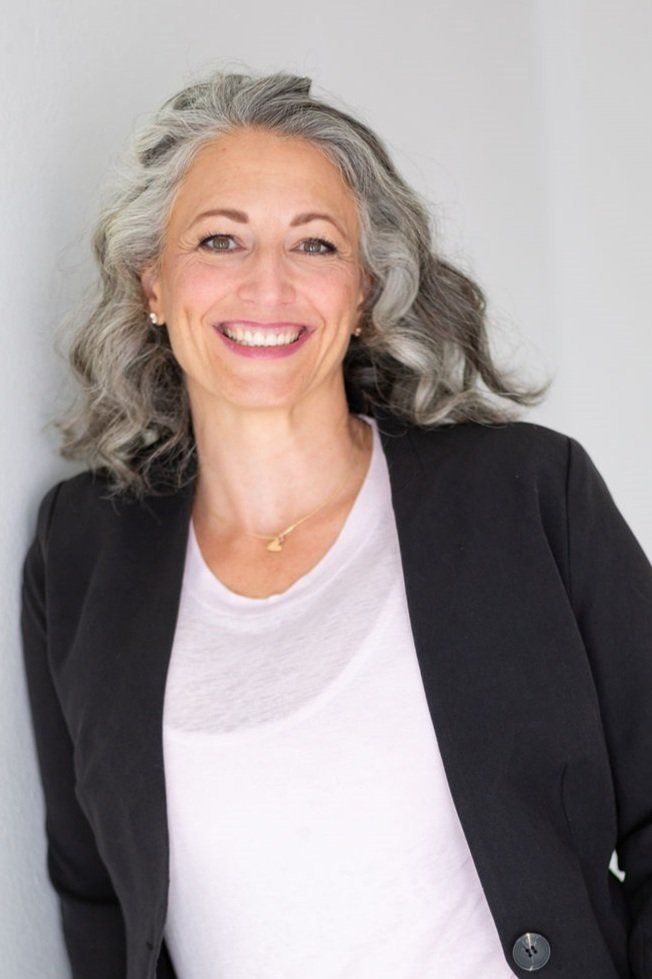 a woman with gray hair and a black jacket is smiling .