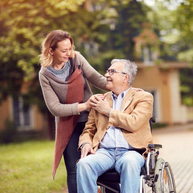 Man In Wheelchair With Carer — Aged Care Services in Paget, QLD