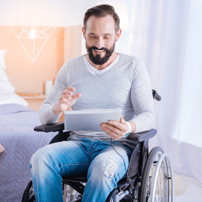 Man In Wheelchair Man Reading iPad — Aged Care Services in Paget, QLD