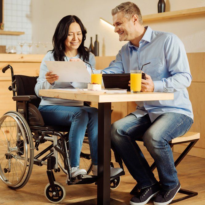 Woman In Wheelchair Reading Document — Aged Care Services in Paget, QLD