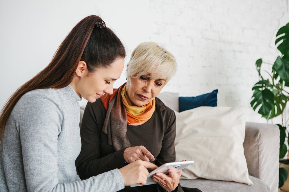 Volunteer Assisting Elderly Woman With Electronic Device — Aged Care Services in Paget, QLD