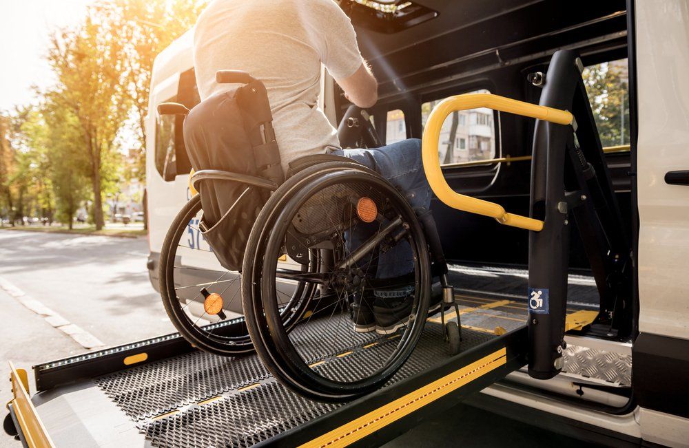 Machine Lifting Man In Wheelchair Into Van — Aged Care Services in Paget, QLD