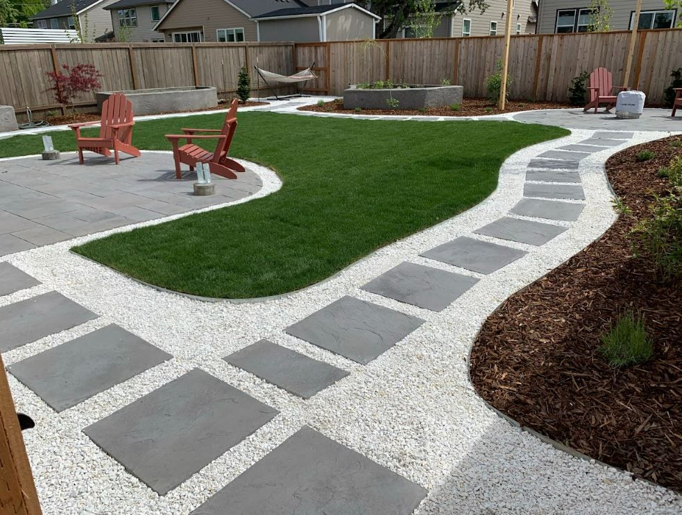 Curved stone walkway around green lawn in a park with orange benches and picnic table