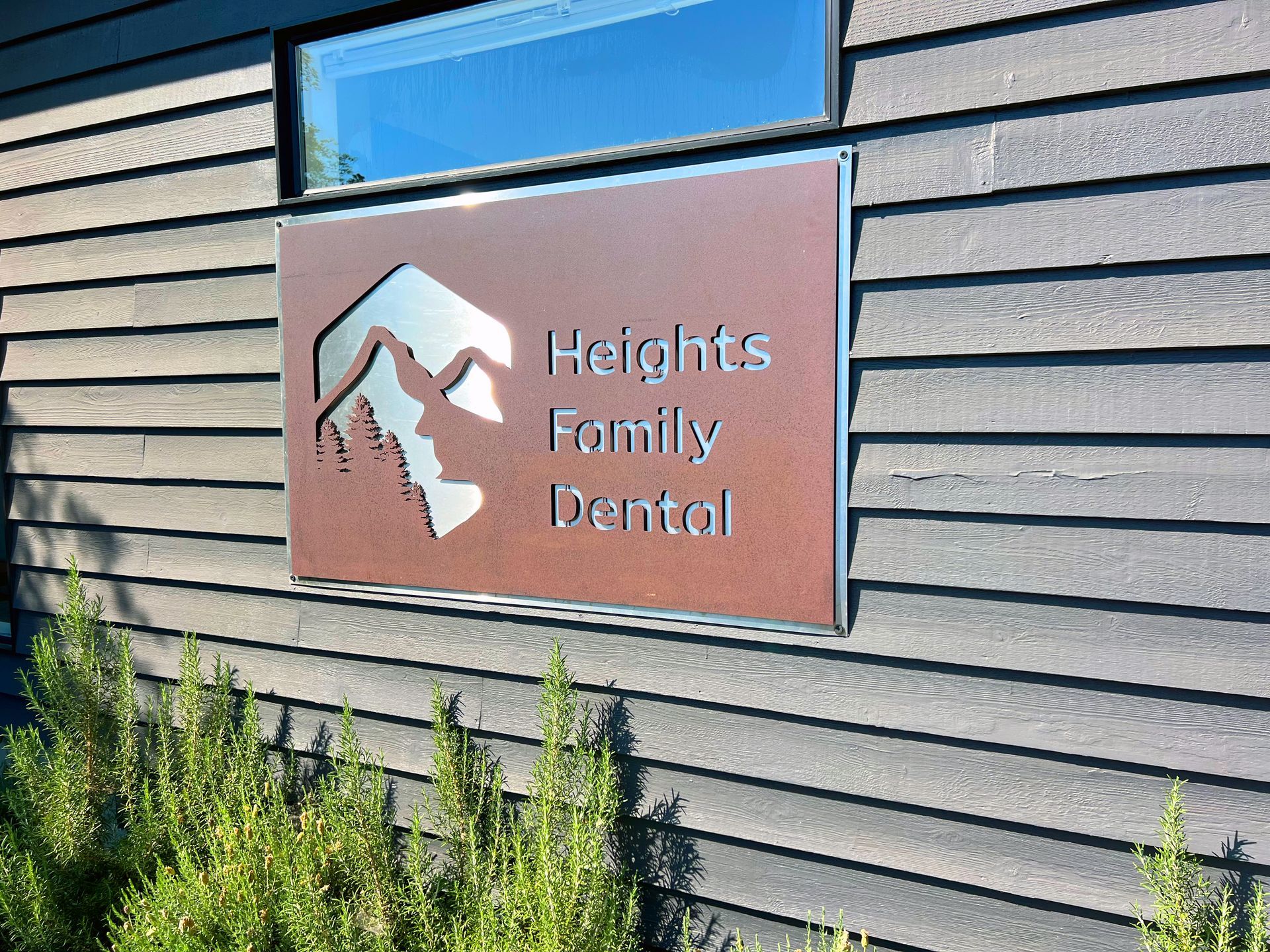 Sign for Heights Family Dental with mountain logo on wood siding.