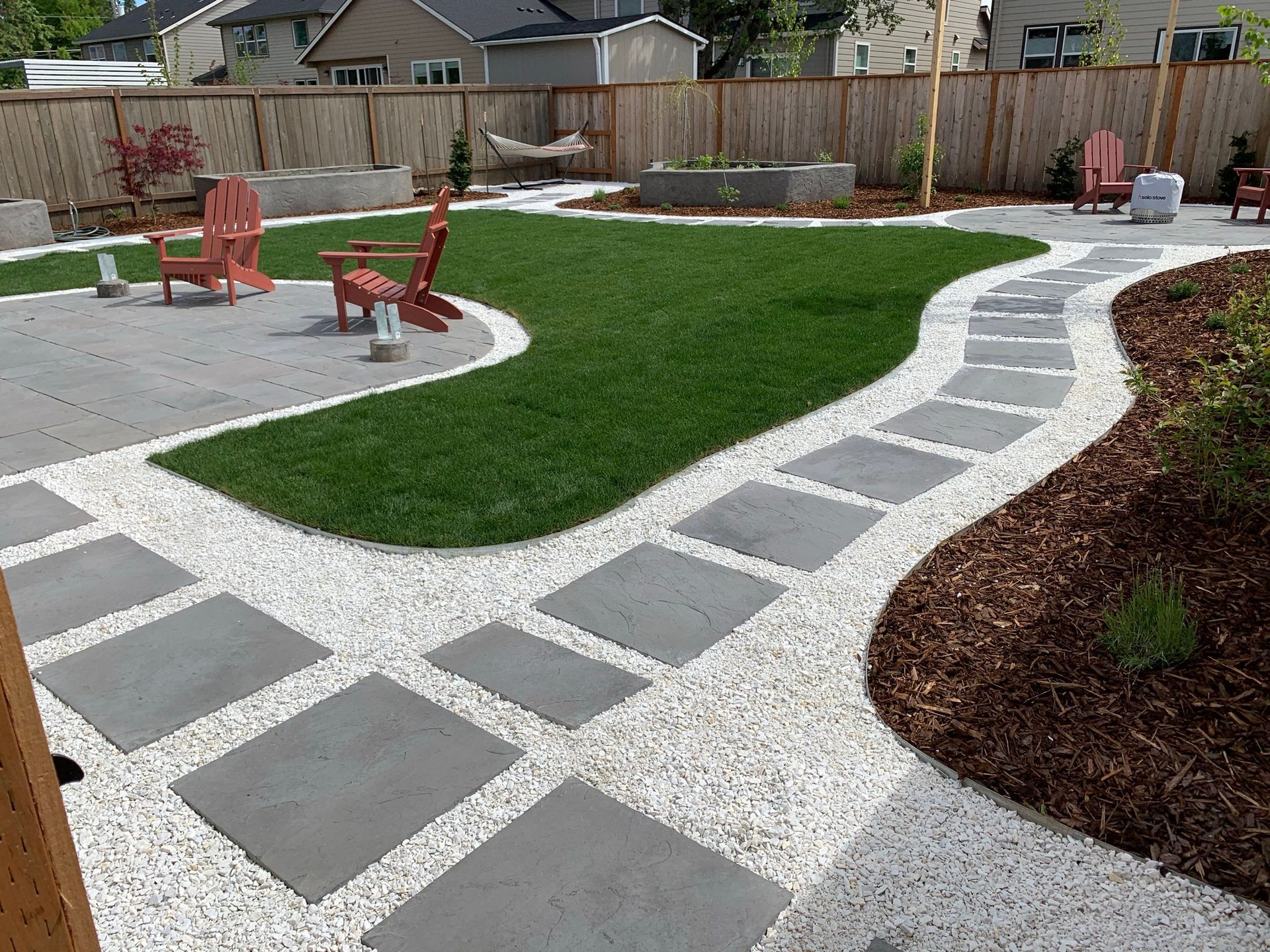Backyard with stepping stones, green grass, and lounge chairs.