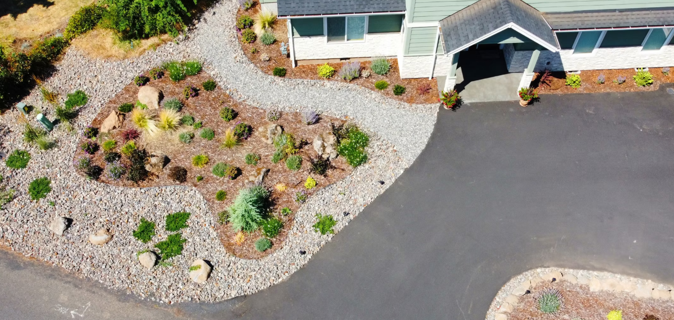 An aerial view of a house with a driveway surrounded by rocks and plants.