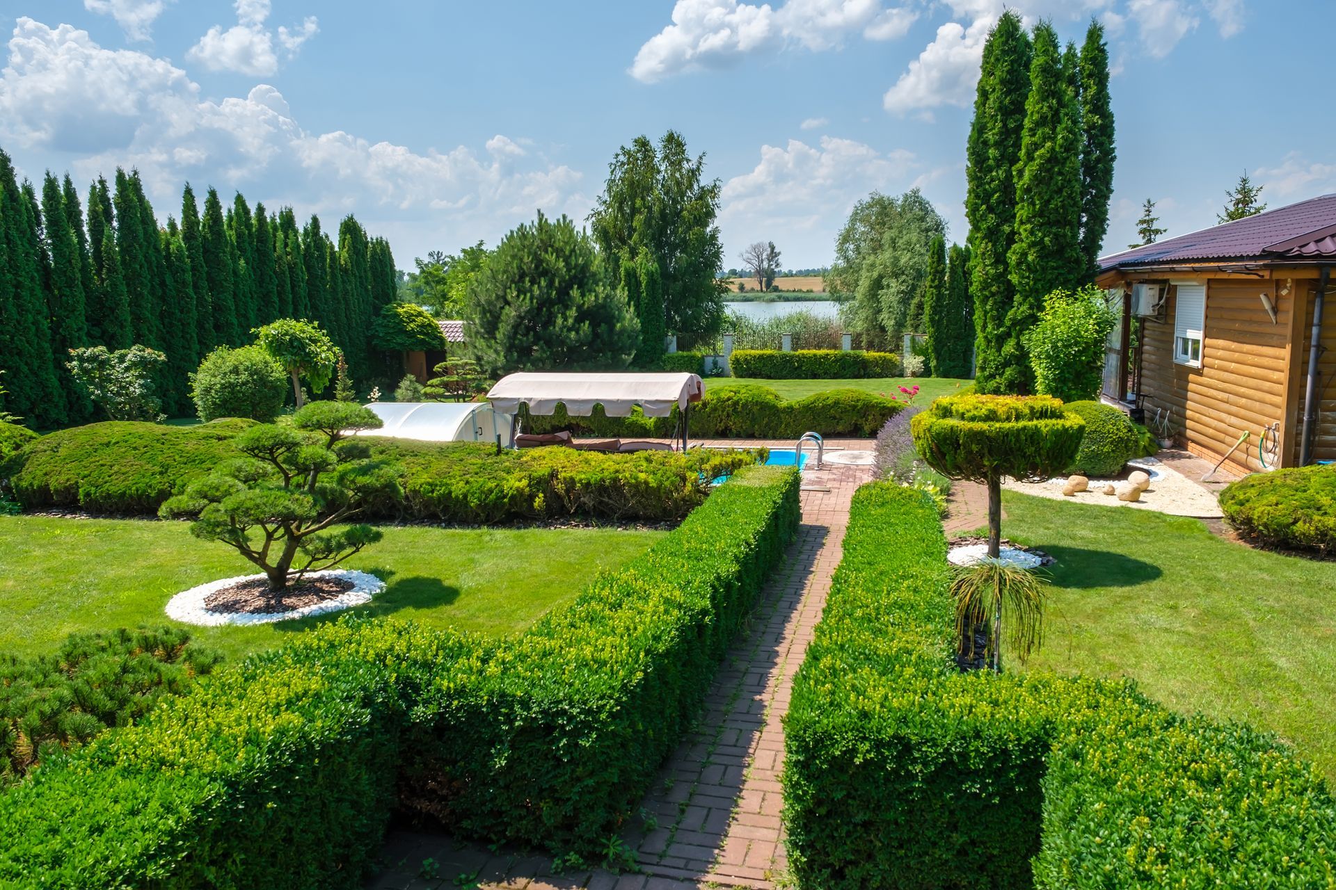 A large lush green garden with a house in the background.