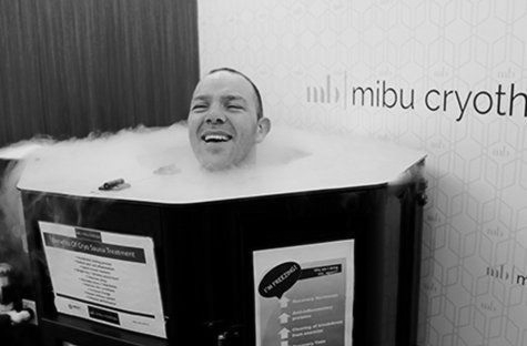 Man smiling in a cryotherapy chamber, surrounded by cold vapor at 