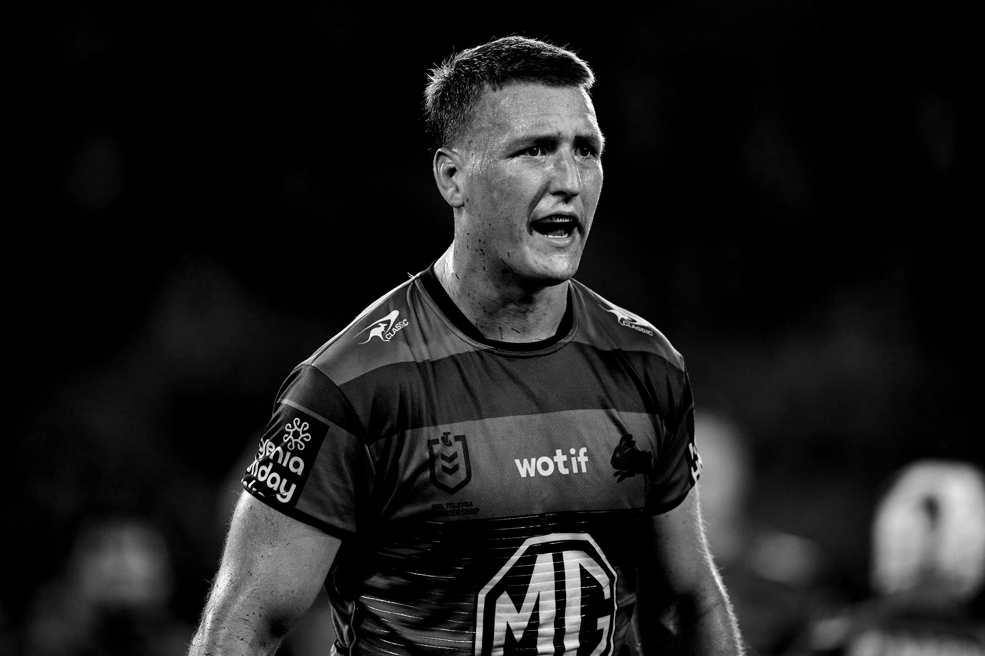 Rugby player in uniform, yelling on the field. Black and white photo.