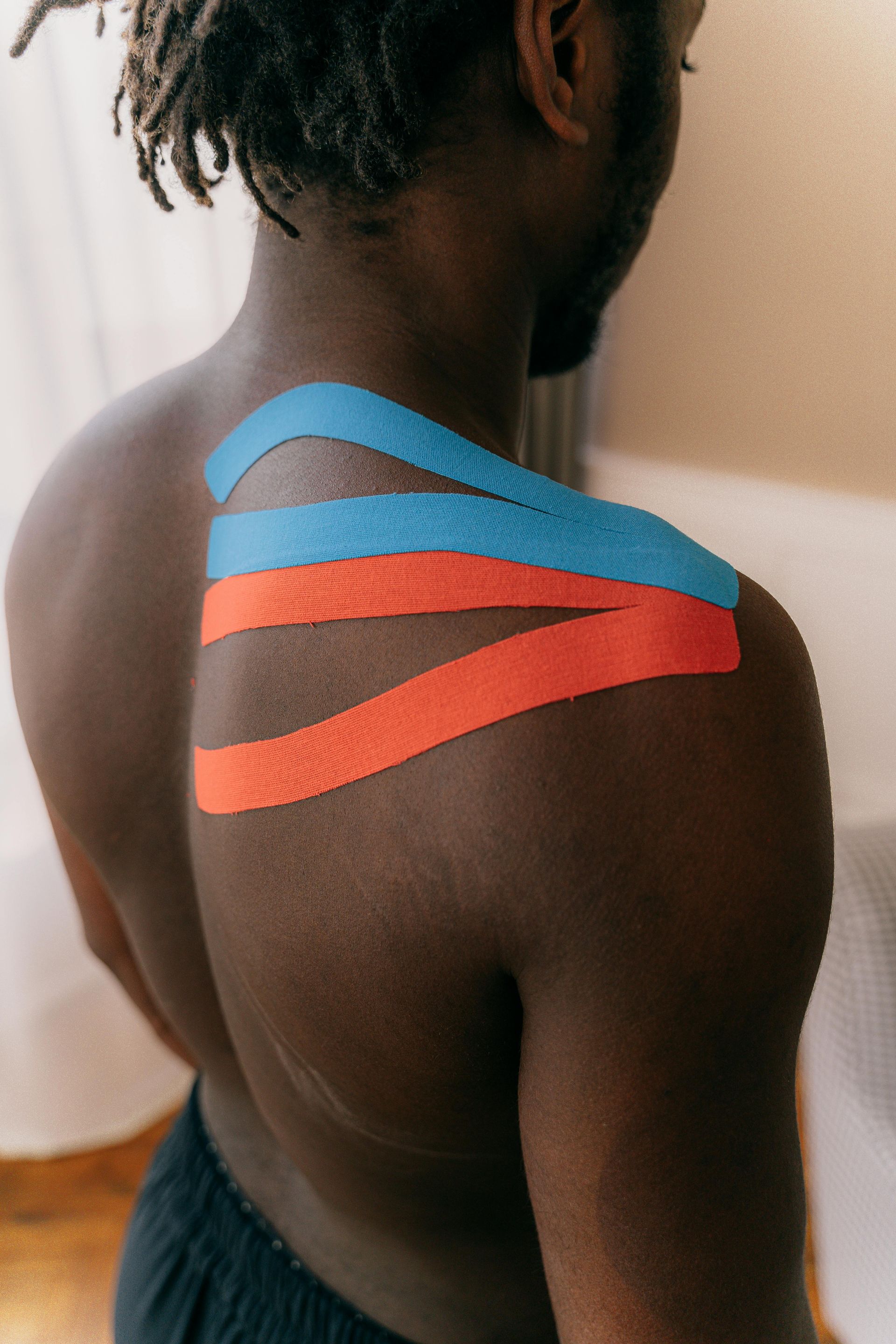 Shoulder with blue and orange kinesiology tape applied.