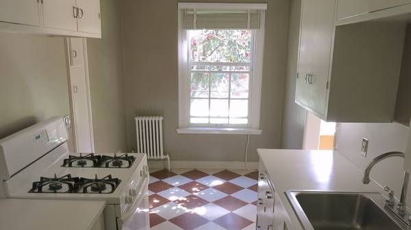 An empty kitchen with a stove , sink and window