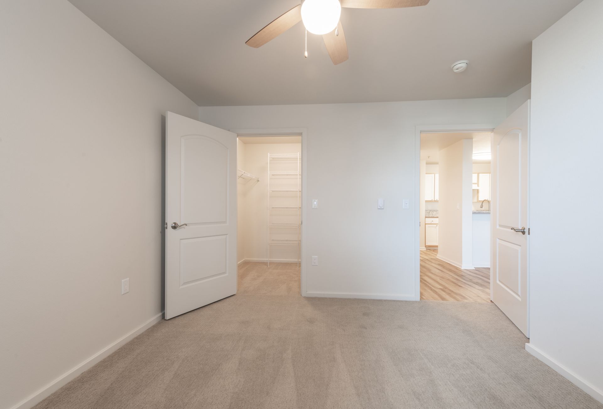 An empty bedroom with a ceiling fan and a walk in closet.