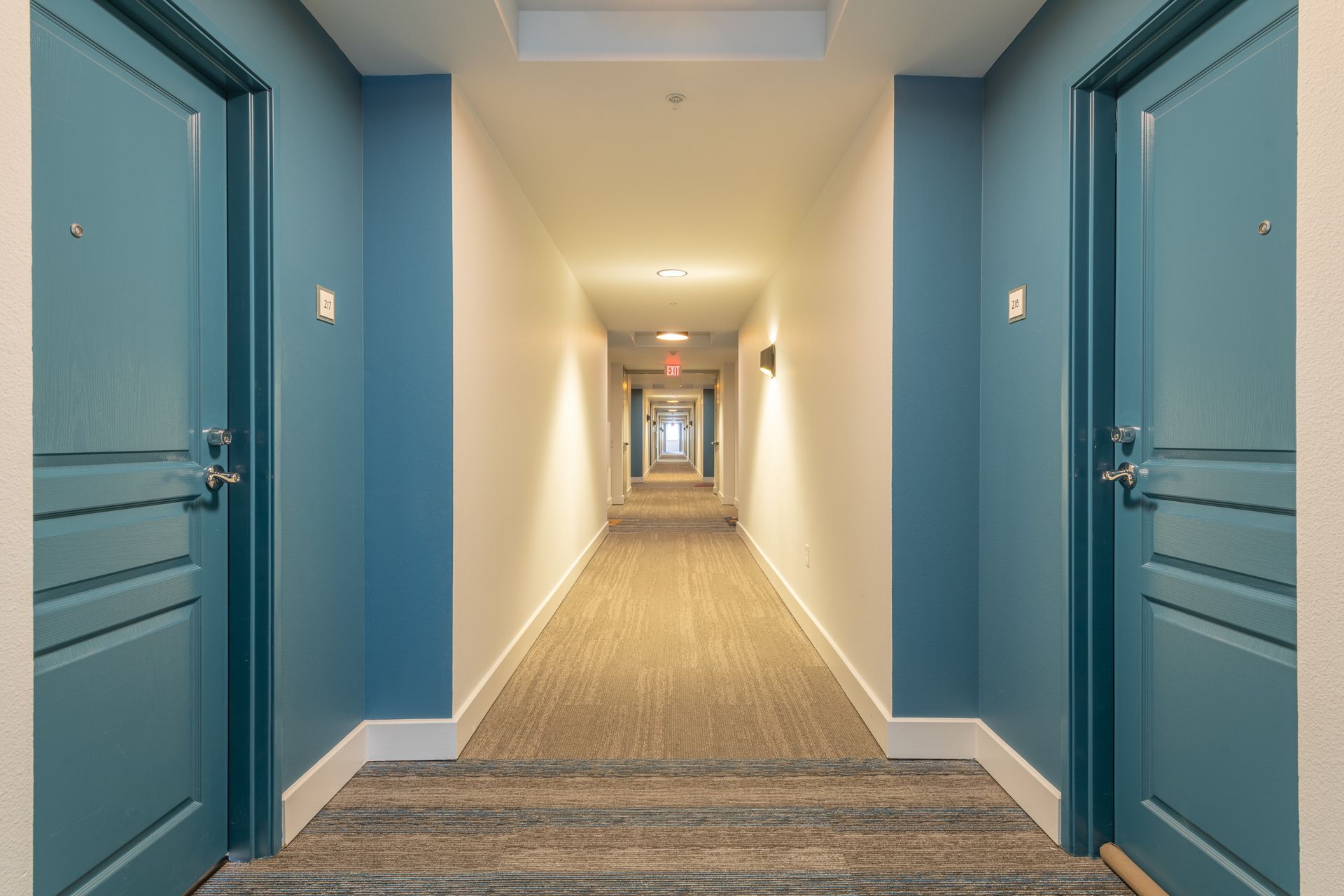 A long hallway with blue doors and white walls.