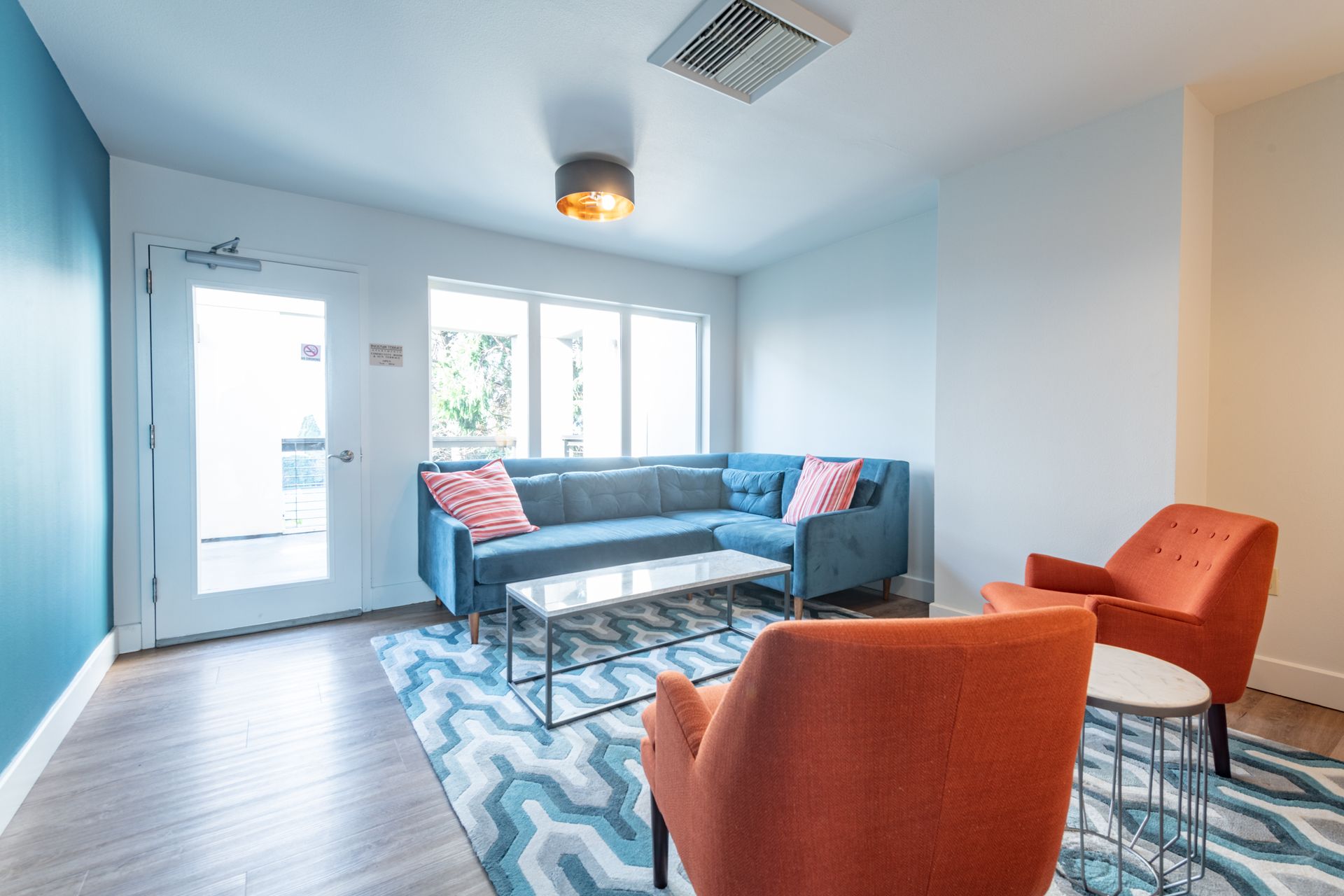 A living room with a blue couch and orange chairs.