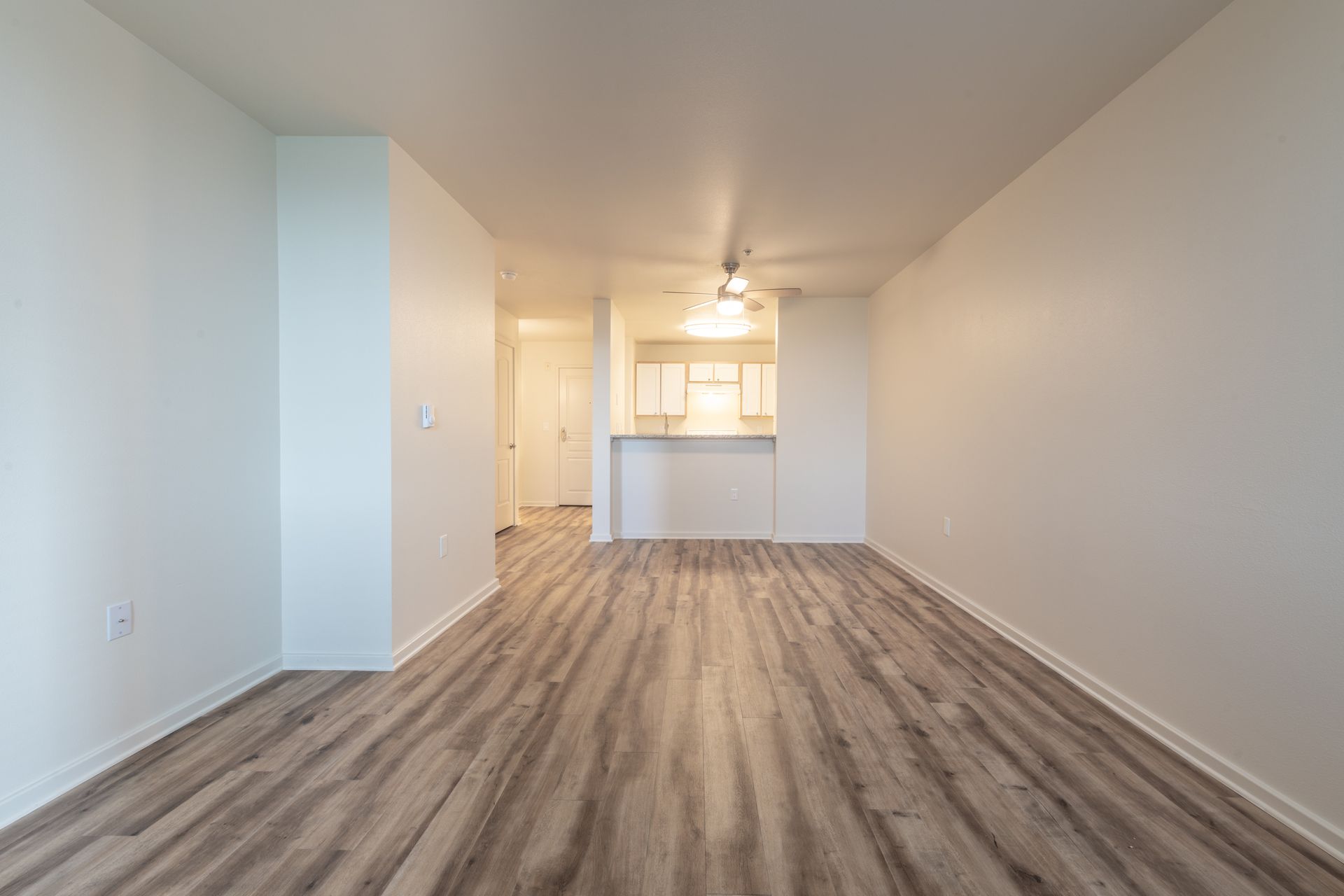 An empty living room with hardwood floors and white walls.