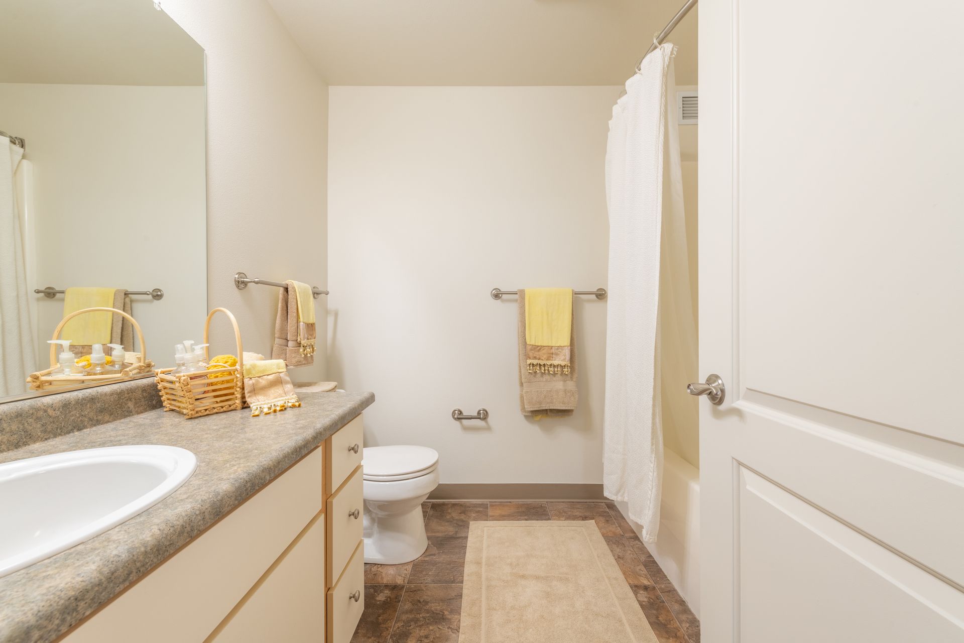 A bathroom with a sink , toilet , shower and mirror.