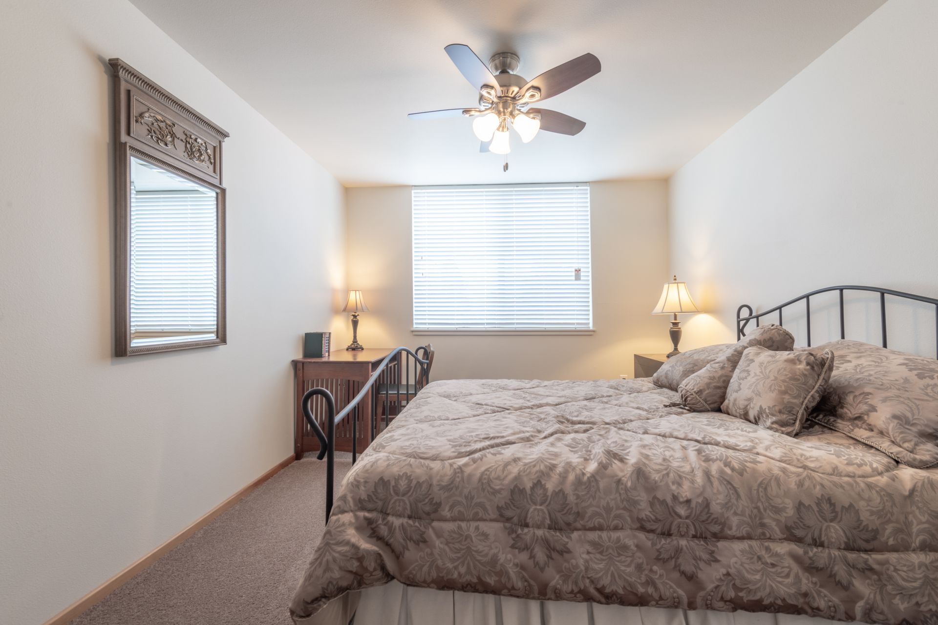 A bedroom with a large bed and a ceiling fan