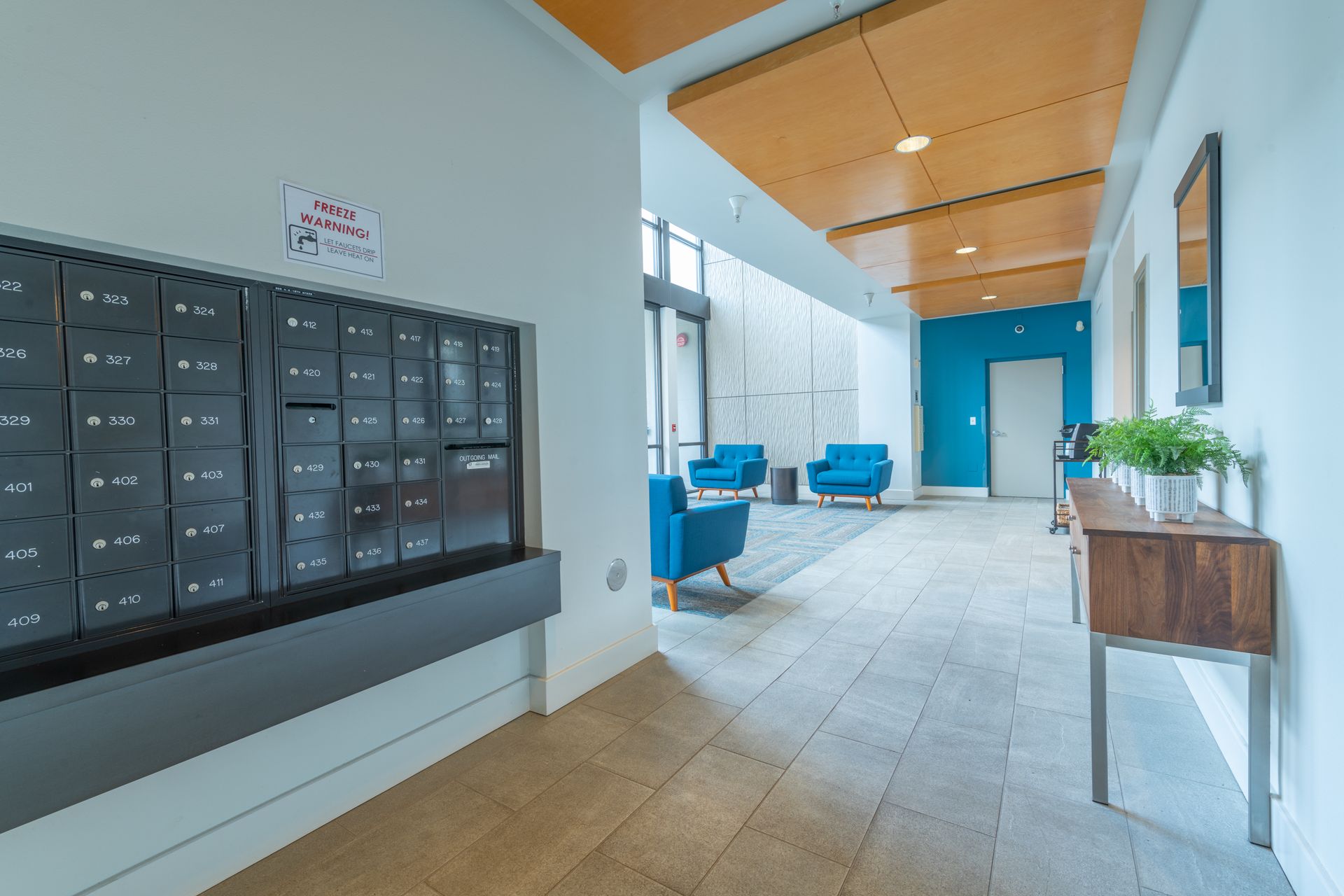 A hallway with a mailbox and chairs in a building.