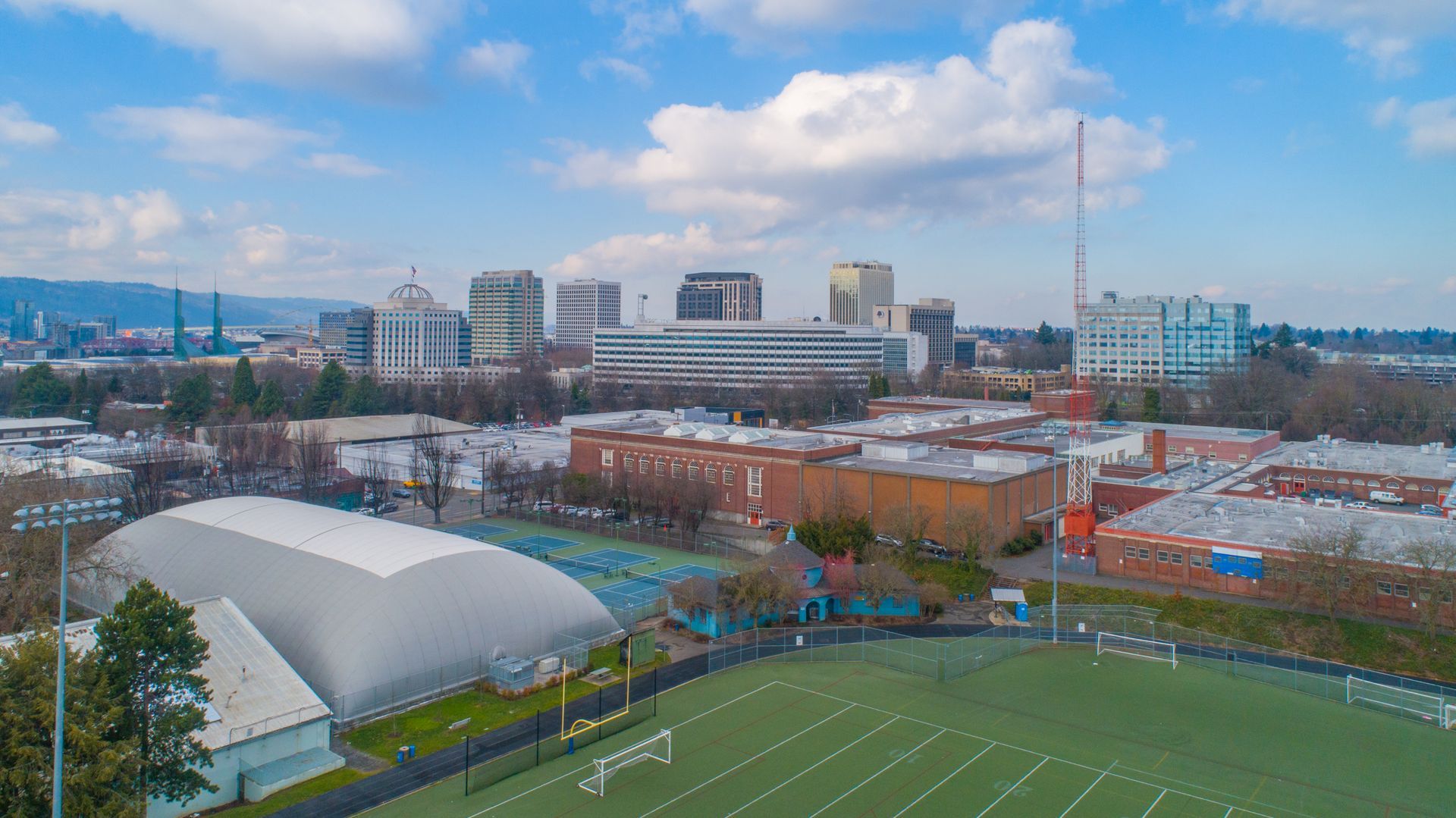 An aerial view of a soccer field with a city in the background.