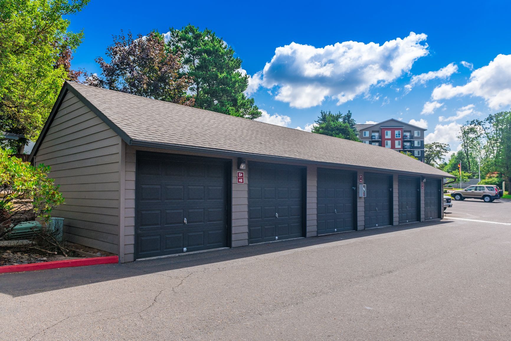 A row of black garage doors are lined up in a parking lot.