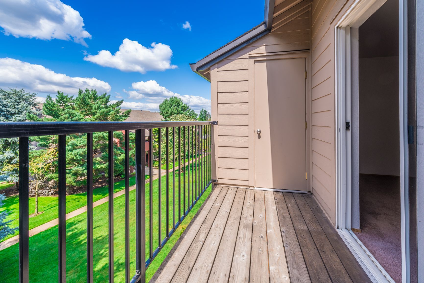 An empty balcony with a metal railing and sliding glass doors.