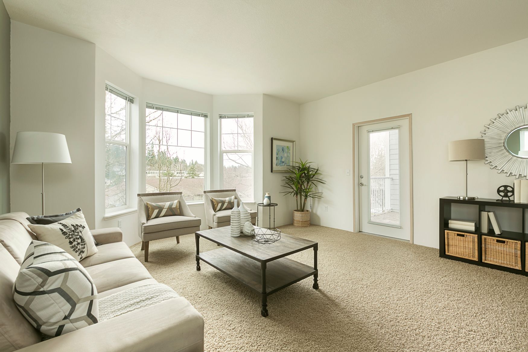 A living room with a couch , chairs , a coffee table and a large window.