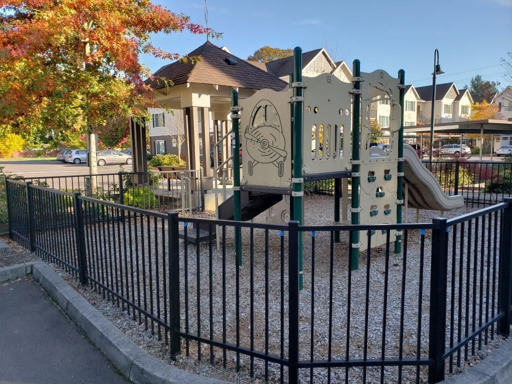 A playground with a fence around it and houses in the background