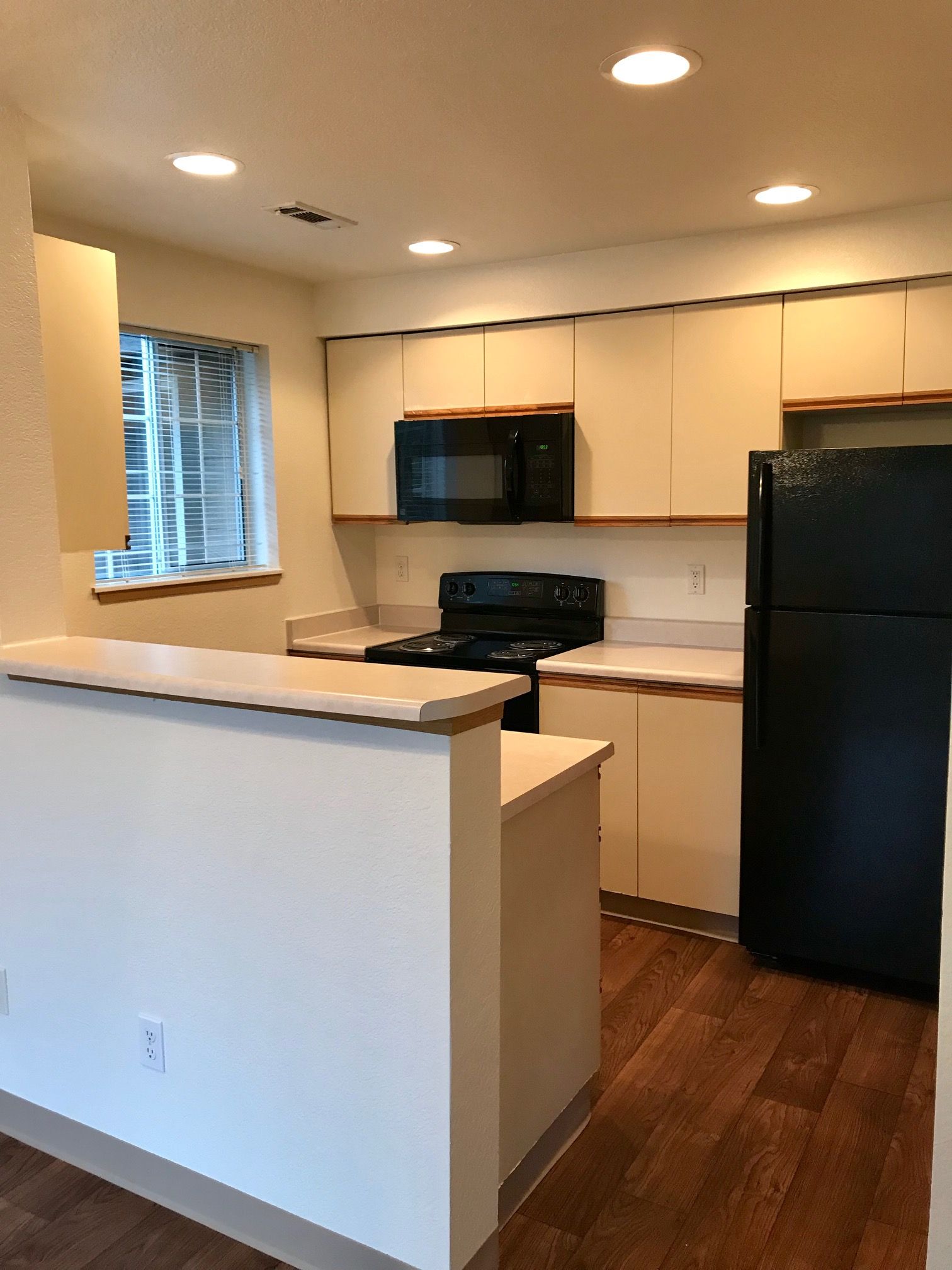 A kitchen with a black refrigerator stove and microwave