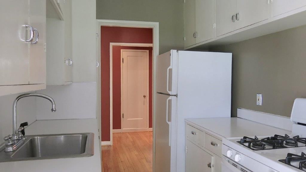 A kitchen with white cabinets and a white refrigerator